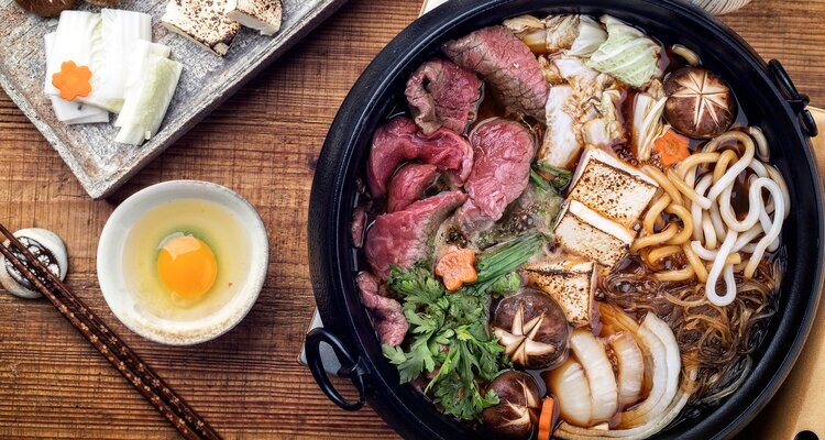 Traditional Sukiyaki pot with Kobe Beef and Vegetable as close-up on wooden table