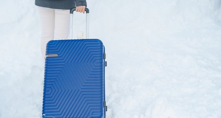 Tourist dragging a luggage suitcase while walking on snowy walkway for a winter travel