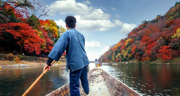 Boating in Arashiyama river with autumn background