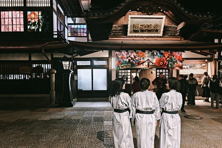 We are wearing yukatas at the entrance of Dōgo Onsen