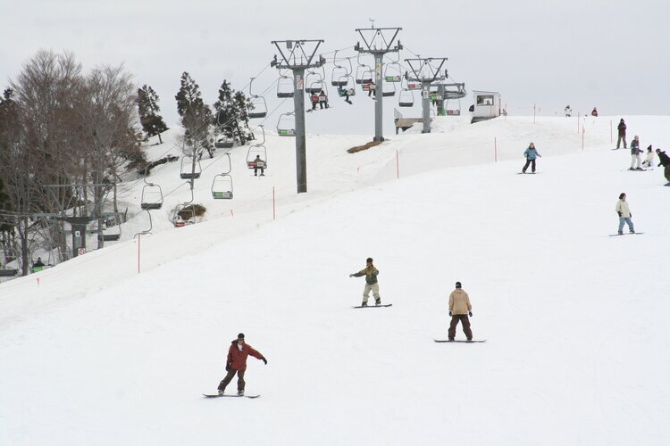 Echigo-Yuzawa resort in Niigata-ken, Japan People sliding down the hill on snowboards, ski lifts, white snow